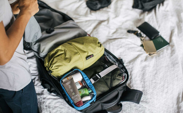 Person packing a Synik 30; one of the items is a 3D Clear Organizer Cube packed with toiletries.